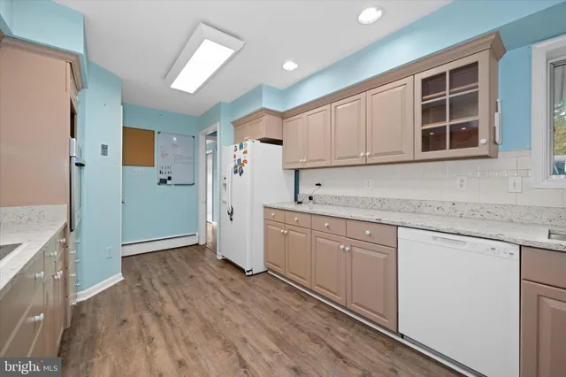 a kitchen with granite countertop white cabinets and refrigerator