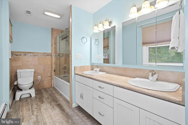 a spacious bathroom with a double vanity sink a mirror and a toilet
