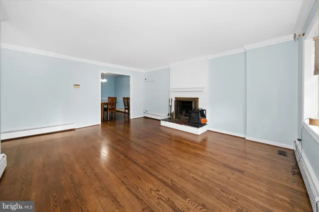 a view of empty room with wooden floor and fireplace