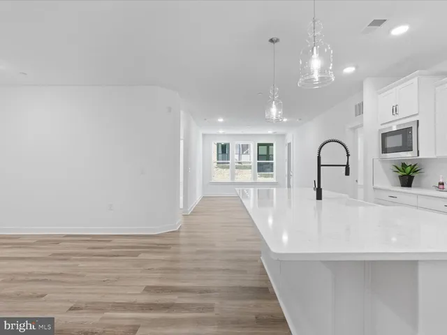 a view of a kitchen with kitchen island a sink wooden floor and living room view