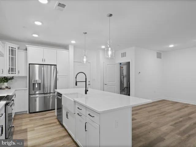 a kitchen with stainless steel appliances kitchen island granite countertop a refrigerator and a sink