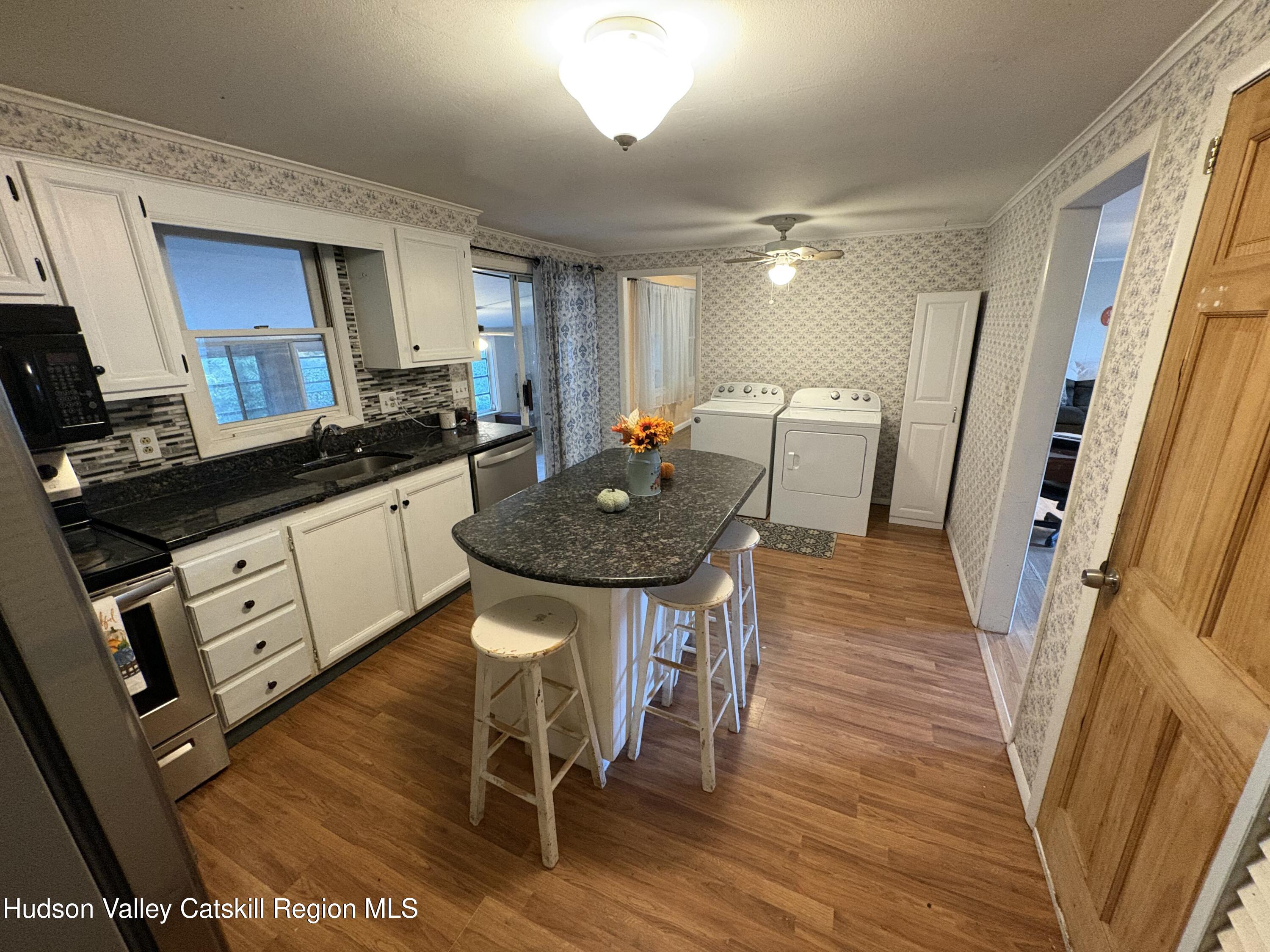 19 Rivenburg Lane Hudson, NY 12534 - Photo 11 of 28 a kitchen with granite countertop a table chairs sink and wooden floor