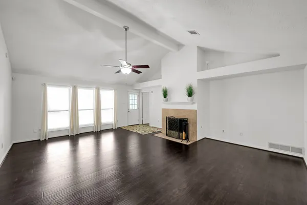 an empty room with wooden floor fireplace and windows