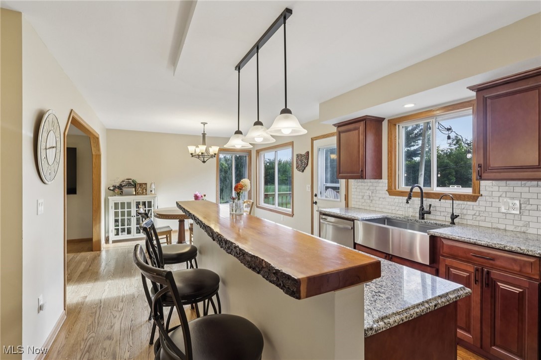 12881 Forest Road Burton, OH 44021 - Photo 27 of 48 Kitchen featuring butcher block counters, breakfast bar, tiled backsplash, hardwood floors, and hanging light fixtures