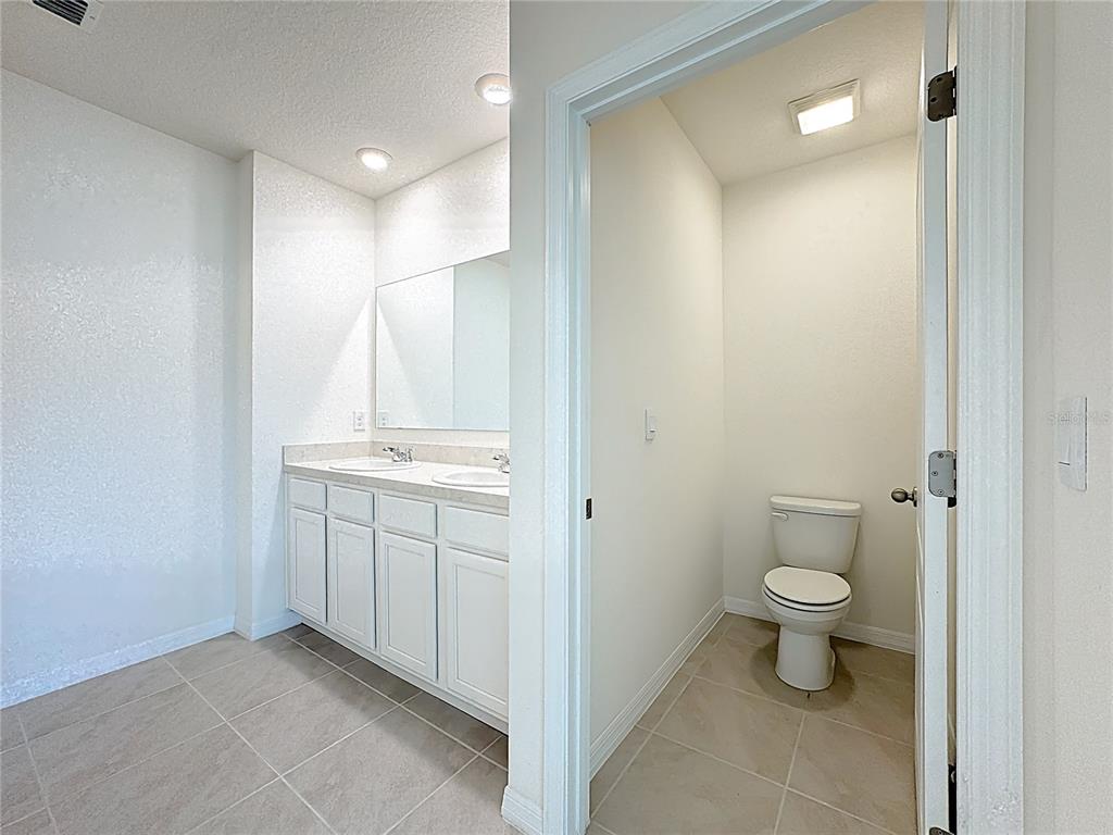 2692 Reddish Egret Bend, Unit 1 St. Cloud, FL 34773 - Photo 26 of 30 a bathroom with a granite countertop sink a toilet and a mirror