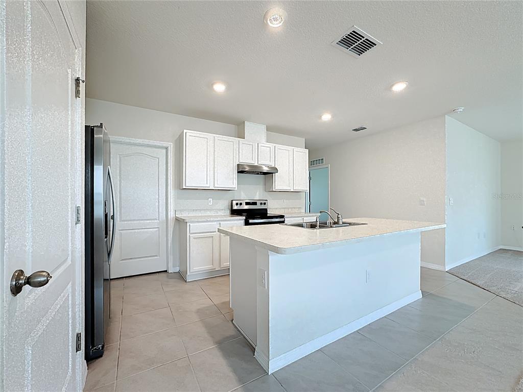 2692 Reddish Egret Bend, Unit 1 St. Cloud, FL 34773 - Photo 5 of 30 a kitchen with kitchen island a sink stainless steel appliances and cabinets