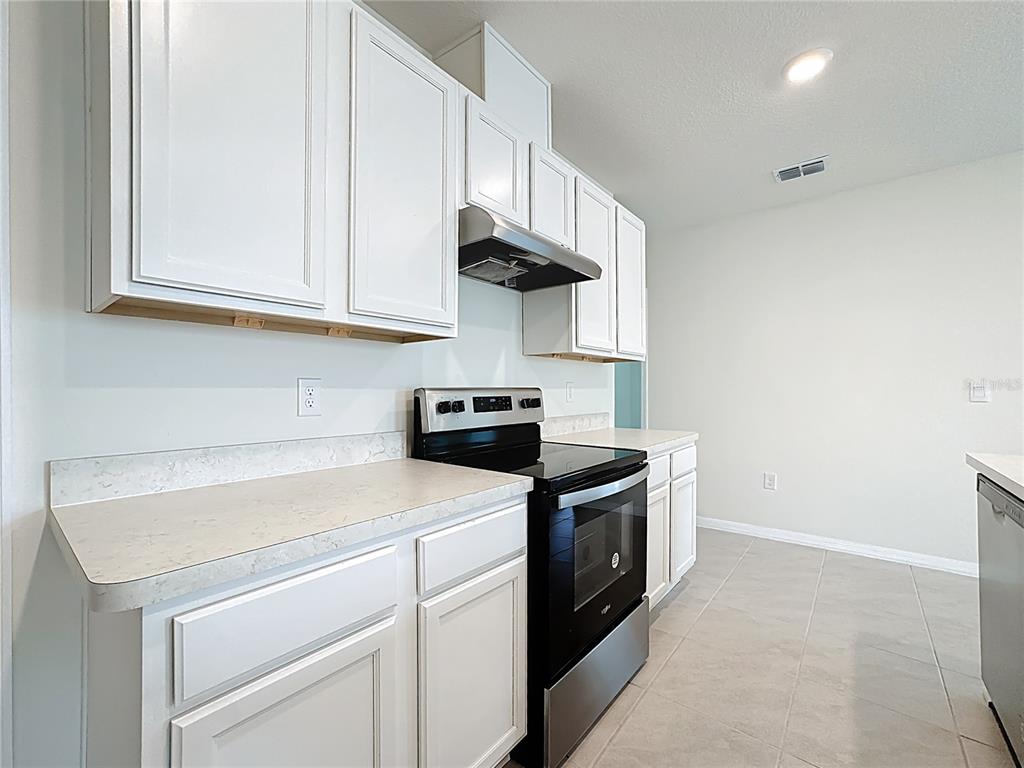 2692 Reddish Egret Bend, Unit 1 St. Cloud, FL 34773 - Photo 6 of 30 a kitchen with stainless steel appliances granite countertop a sink a stove and a microwave