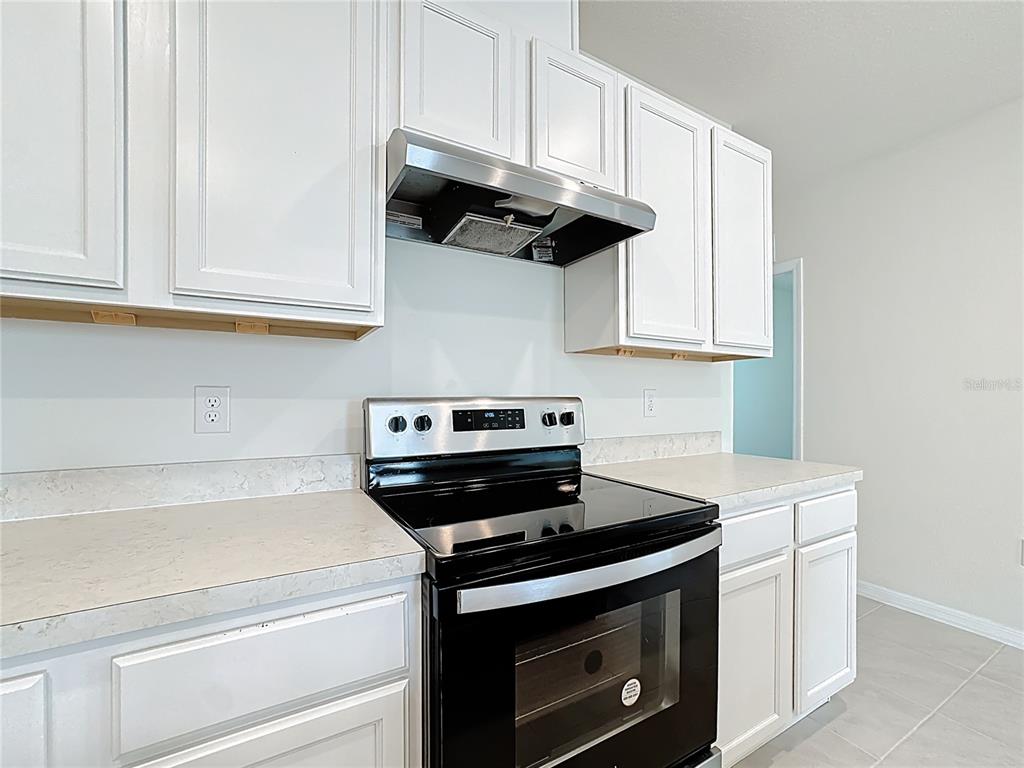 2692 Reddish Egret Bend, Unit 1 St. Cloud, FL 34773 - Photo 7 of 30 a kitchen with stainless steel appliances granite countertop white cabinets and a stove top oven