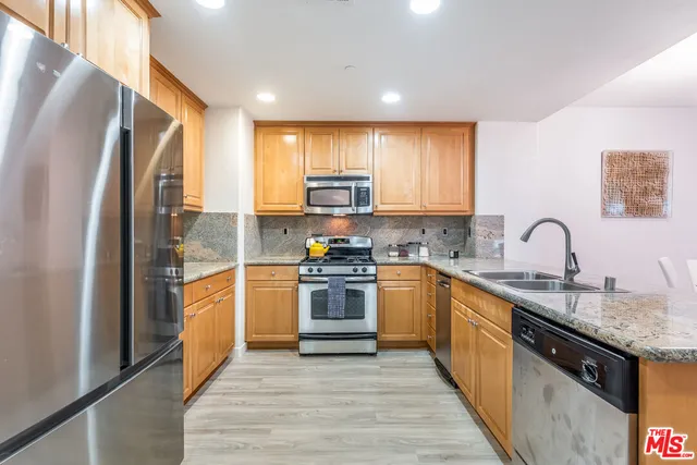 a kitchen with granite countertop a refrigerator stove top oven and sink