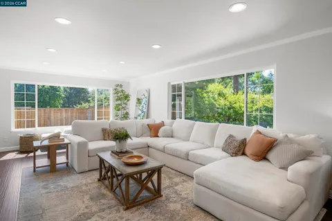a living room with furniture a large window and dining table