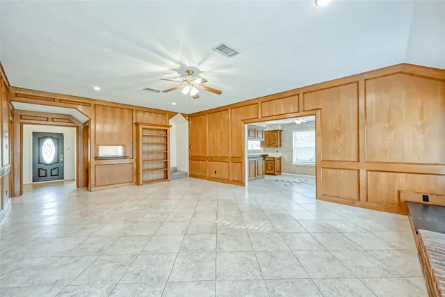 a view of an empty room with window and chandelier