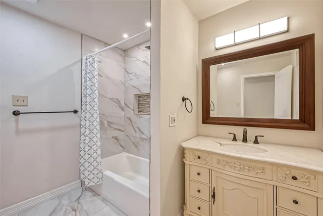 a bathroom with a bathtub shower sink vanity and mirror