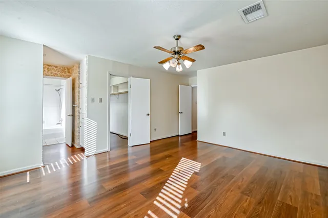 an empty room with wooden floor and a ceiling fan