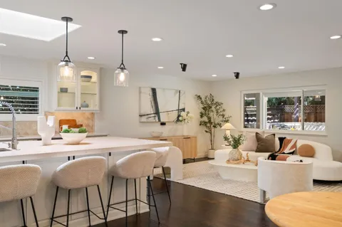 a view of a dining room and livingroom with furniture wooden floor a rug a chandelier and a view