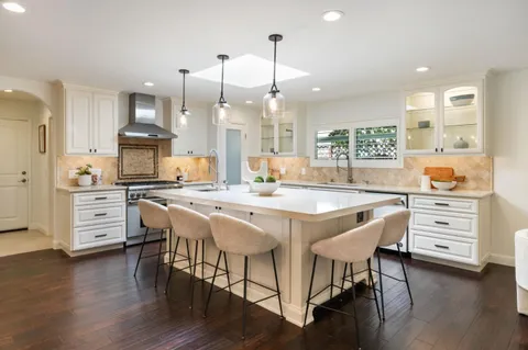 a kitchen with stainless steel appliances a dining table chairs stove and cabinets