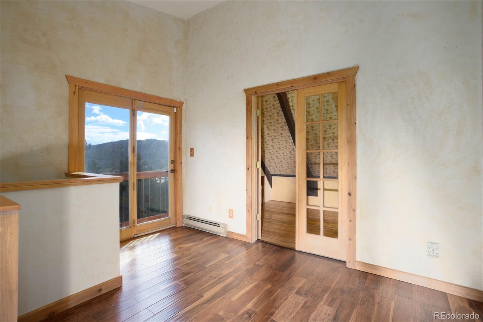 9209 Fallen Rock Road Conifer, CO 80433 - Photo 18 of 33 an empty room with wooden floor and windows