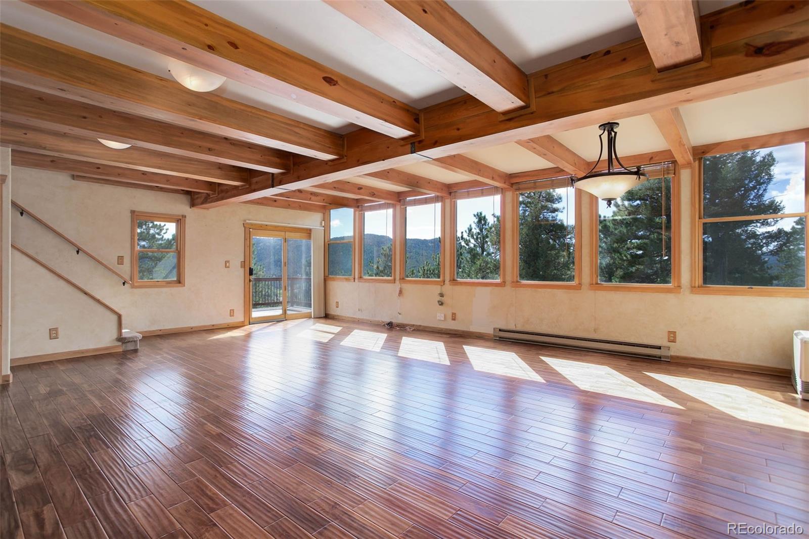 9209 Fallen Rock Road Conifer, CO 80433 - Photo 5 of 33 a view of an empty room with wooden floor and windows