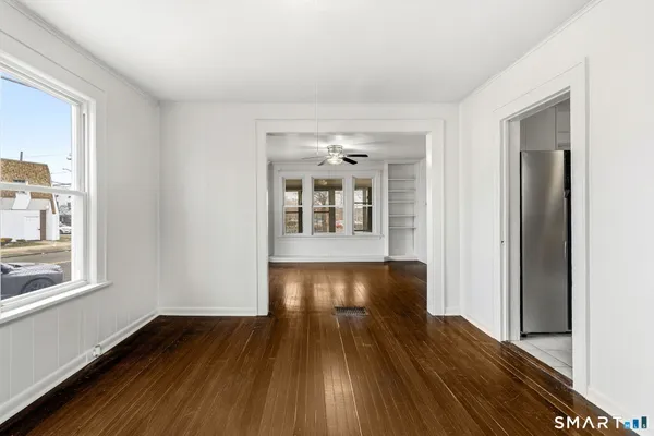 a view of an empty room with wooden floor and a window