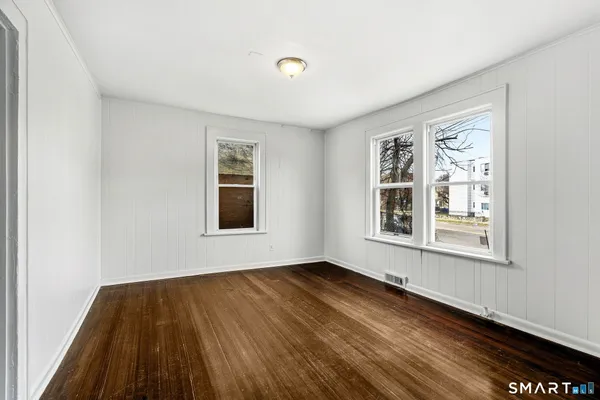 a view of an empty room with wooden floor and a window