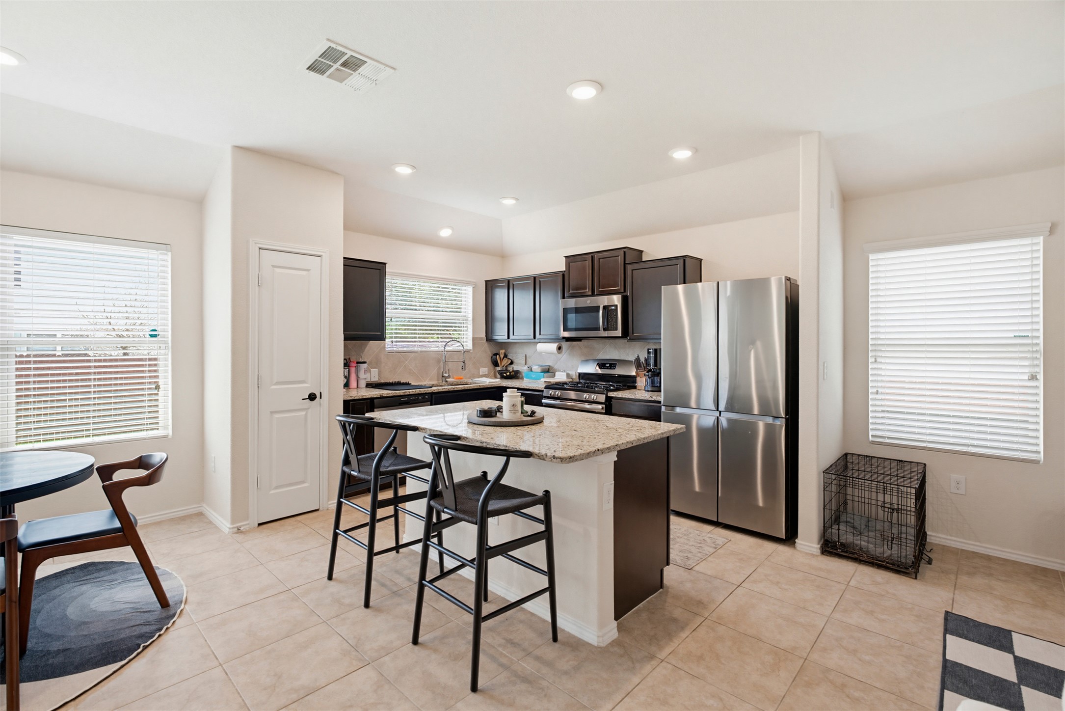 5705 Southerner Way Austin, TX 78747 - Photo 3 of 22 A well-lit kitchen boasts dark cabinetry, stainless steel appliances, and a central island with bar seating.