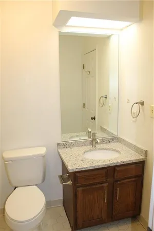 a bathroom with a granite countertop toilet sink and mirror