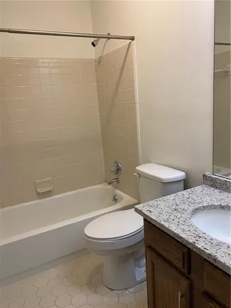 a bathroom with a granite countertop bathtub shower sink vanity and toilet