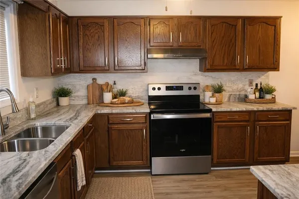 a kitchen with stainless steel appliances granite countertop a stove a sink dishwasher and a microwave oven with wooden cabinets