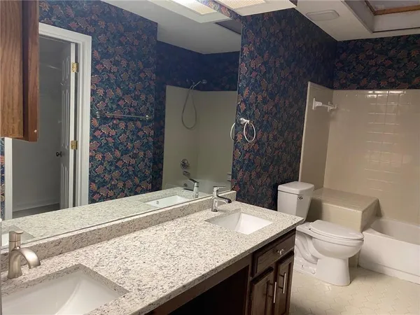 a bathroom with a granite countertop sink toilet and shower