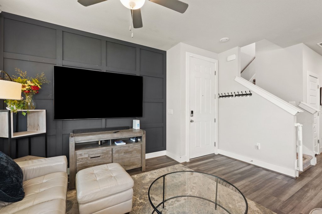 7403 Travertine Spring Drive, Unit 117 Austin, TX 78744 - Photo 10 of 37 Board and batten accent wall frames the media area, contrasting with light walls and wood-look flooring.
