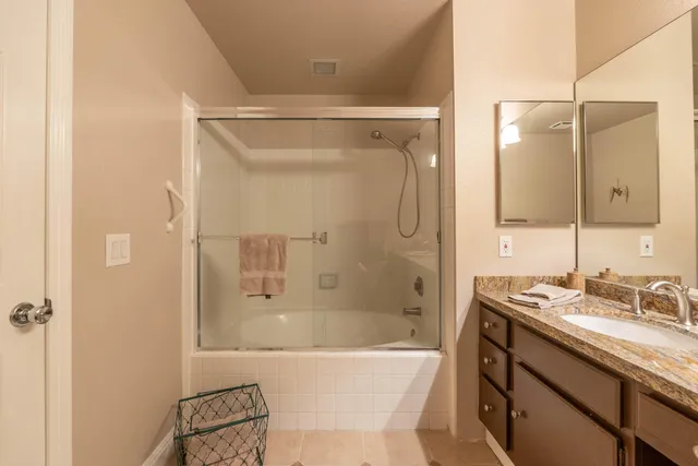 a bathroom with a granite countertop sink a toilet a mirror and shower curtains