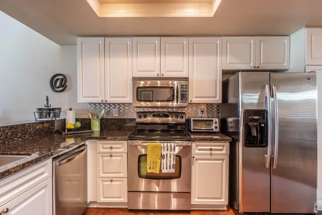 a large kitchen with granite countertop a sink and cabinets