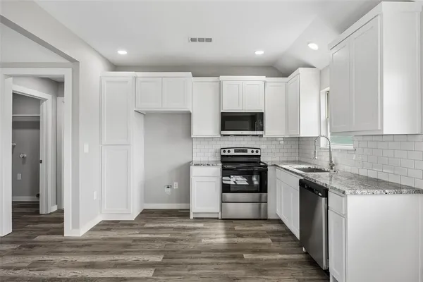 a kitchen with granite countertop a stove top oven and cabinets