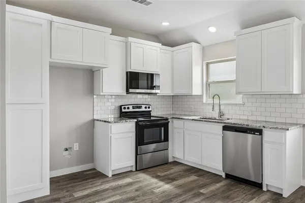 a kitchen with cabinets stainless steel appliances and wooden floor
