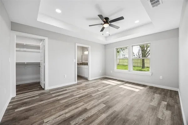 a view of an empty room with a window and wooden floor