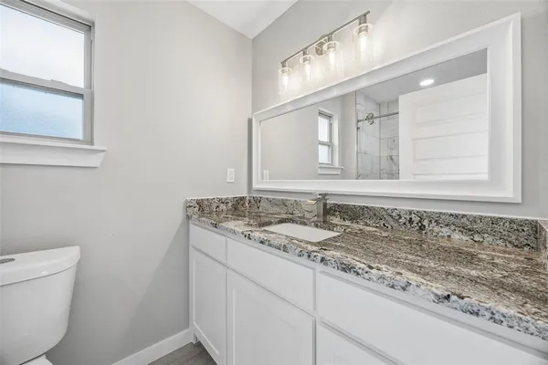 a bathroom with a granite countertop sink a toilet and a mirror