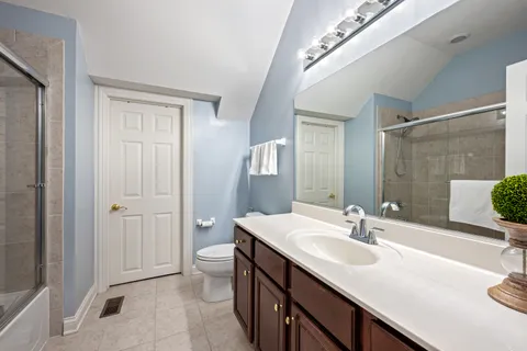 a bathroom with a double vanity sink and mirror with toilet