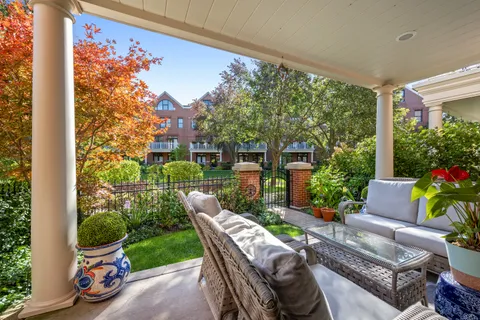 a view of a patio with couches table and chairs potted plants with wooden floor and fence