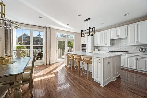 a kitchen with stainless steel appliances granite countertop a stove top oven a sink dishwasher a dining table and chairs with wooden floor