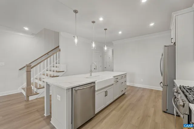 a kitchen with a sink a counter top space stainless steel appliances and wooden floor