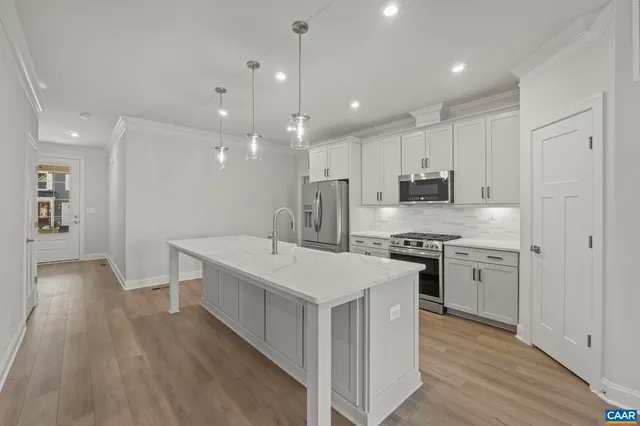 a large kitchen with stainless steel appliances lots of counter space and wooden floors