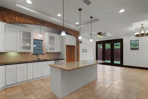 a large kitchen with granite countertop a large counter top a sink stainless steel appliances and cabinets