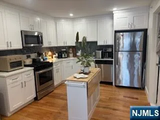 a kitchen with kitchen island granite countertop stainless steel appliances a refrigerator a stove top oven a sink and cabinets