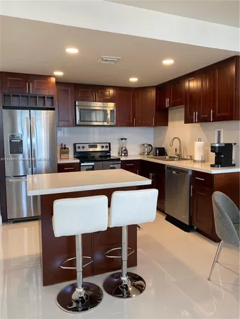 a kitchen with stainless steel appliances granite countertop a sink a stove a refrigerator cabinets and chairs