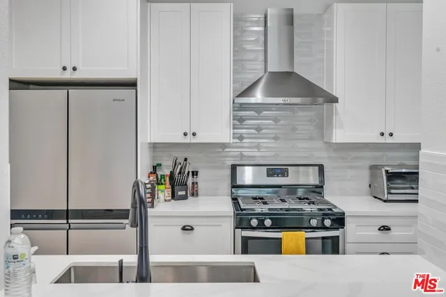 a kitchen with stainless steel appliances granite countertop a stove and a white cabinets