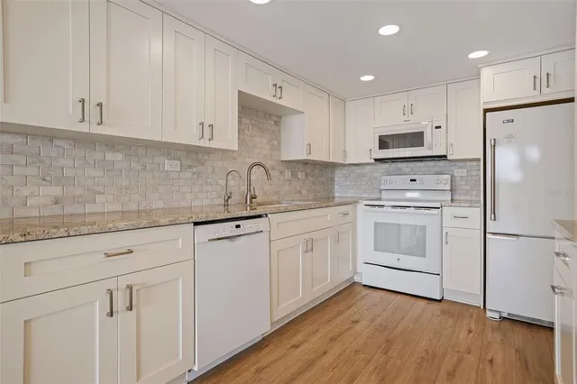 a kitchen with white cabinets white appliances and sink