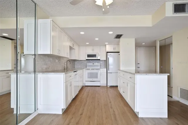 a kitchen with kitchen island white cabinets stainless steel appliances and a sink