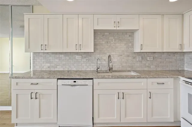a kitchen with white cabinets and sink