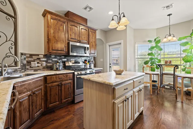 a kitchen with stainless steel appliances granite countertop a sink stove and cabinets