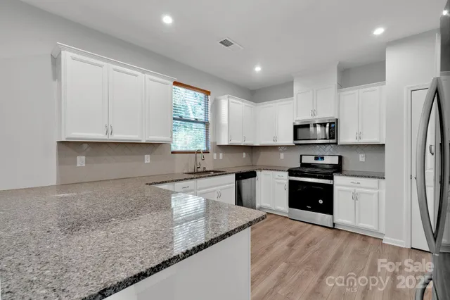 a kitchen with stainless steel appliances granite countertop a refrigerator sink and stove