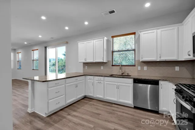 a kitchen with granite countertop white cabinets and wooden floor